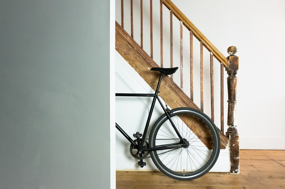bicicleta preta e cinza apoiada na parede branca