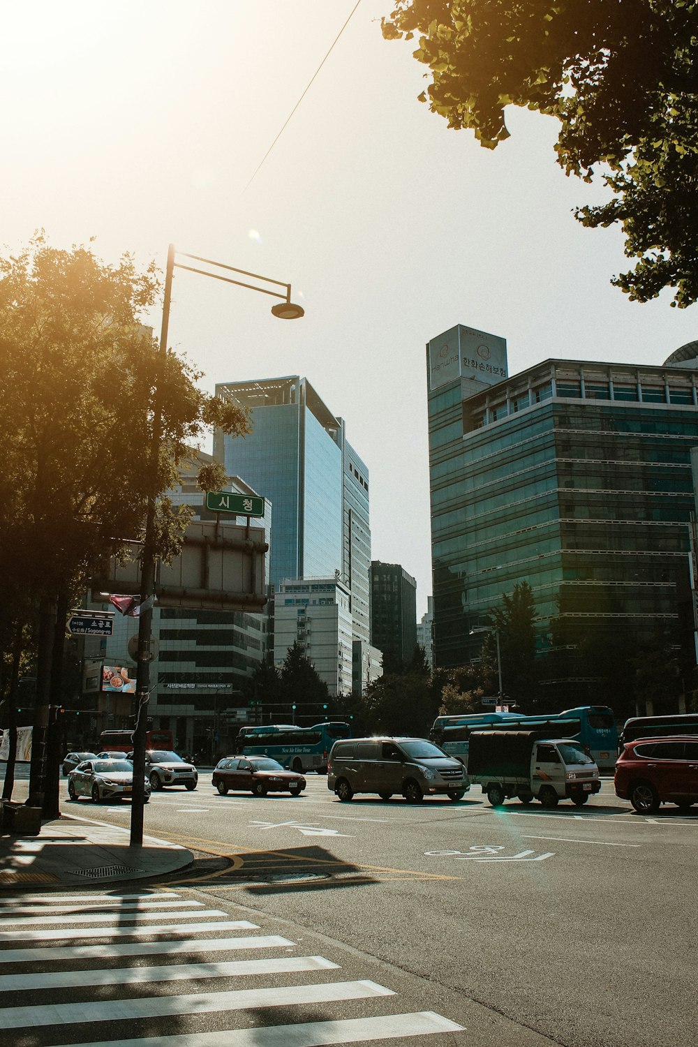 cars parked on side of road near high rise buildings during daytime