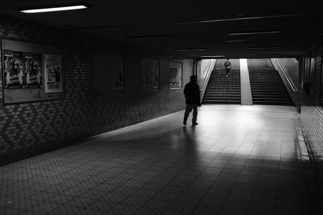 grayscale photo of woman walking on hallway