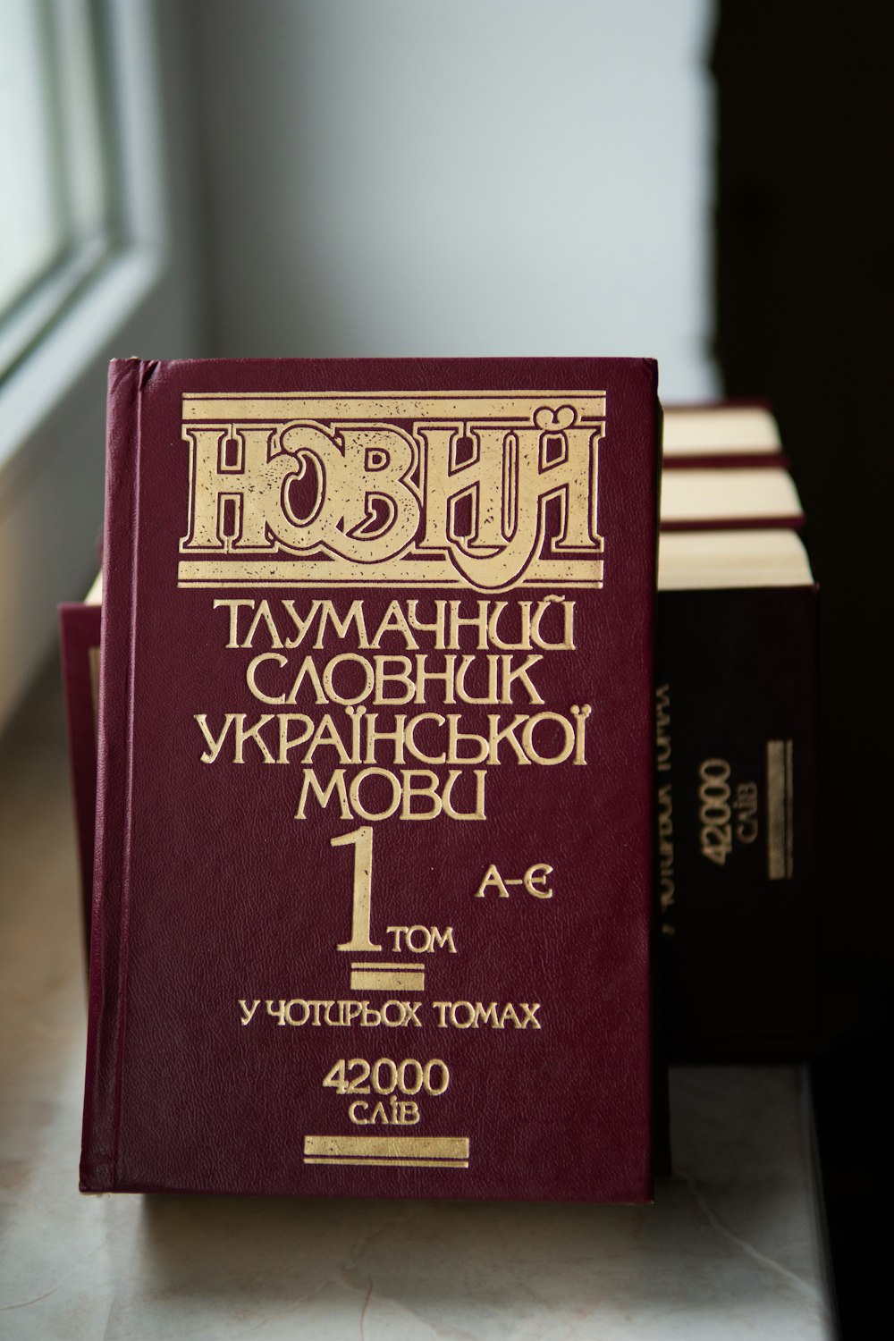 a red book sitting on top of a counter next to a window