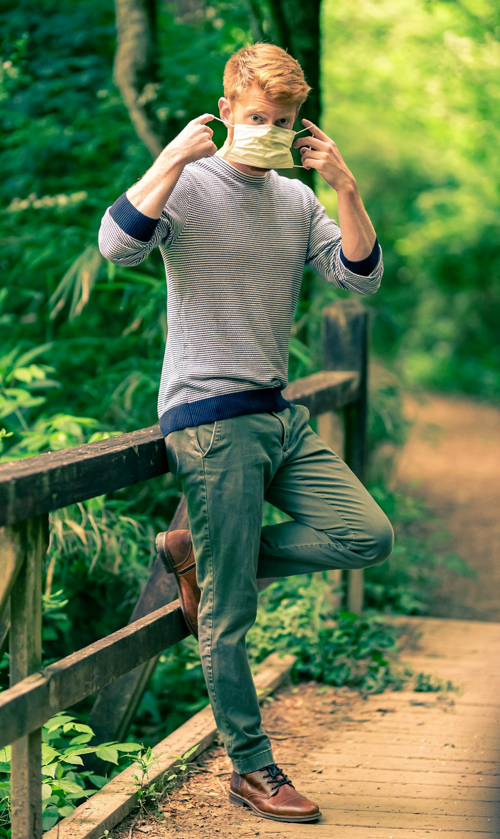 man in gray and white striped long sleeve shirt and green pants sitting on brown wooden