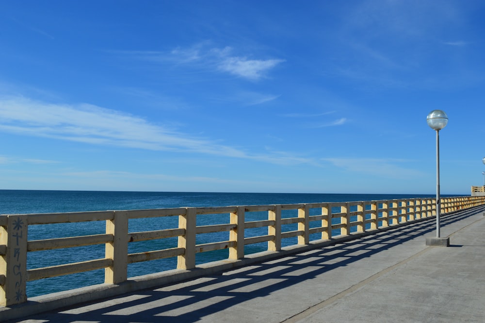 昼間の青空の下、青い海に架かる茶色の木橋