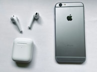 Display of different iPhone models alongside compatible AirPods and charging cables on a deep blue cloth.