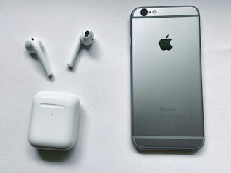 Display of different iPhone models alongside compatible AirPods and charging cables on a deep blue cloth.