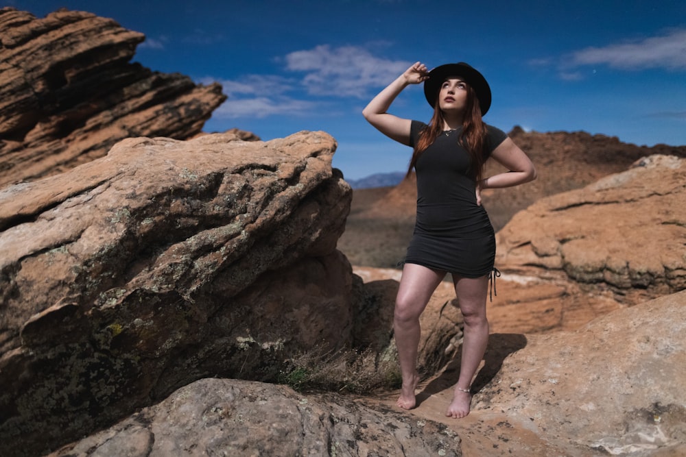 woman in black tank top and black shorts standing on brown rock during daytime