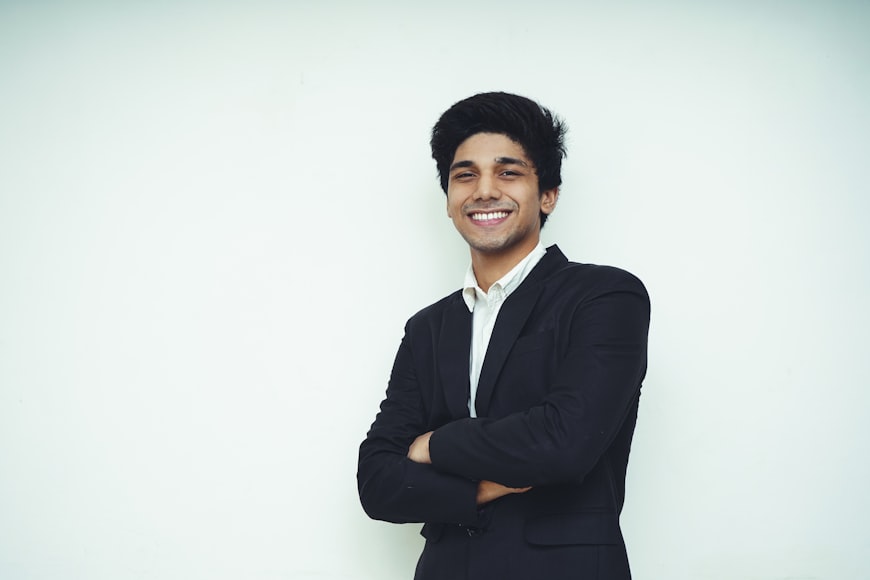 Man in black suit standing in front of white wall