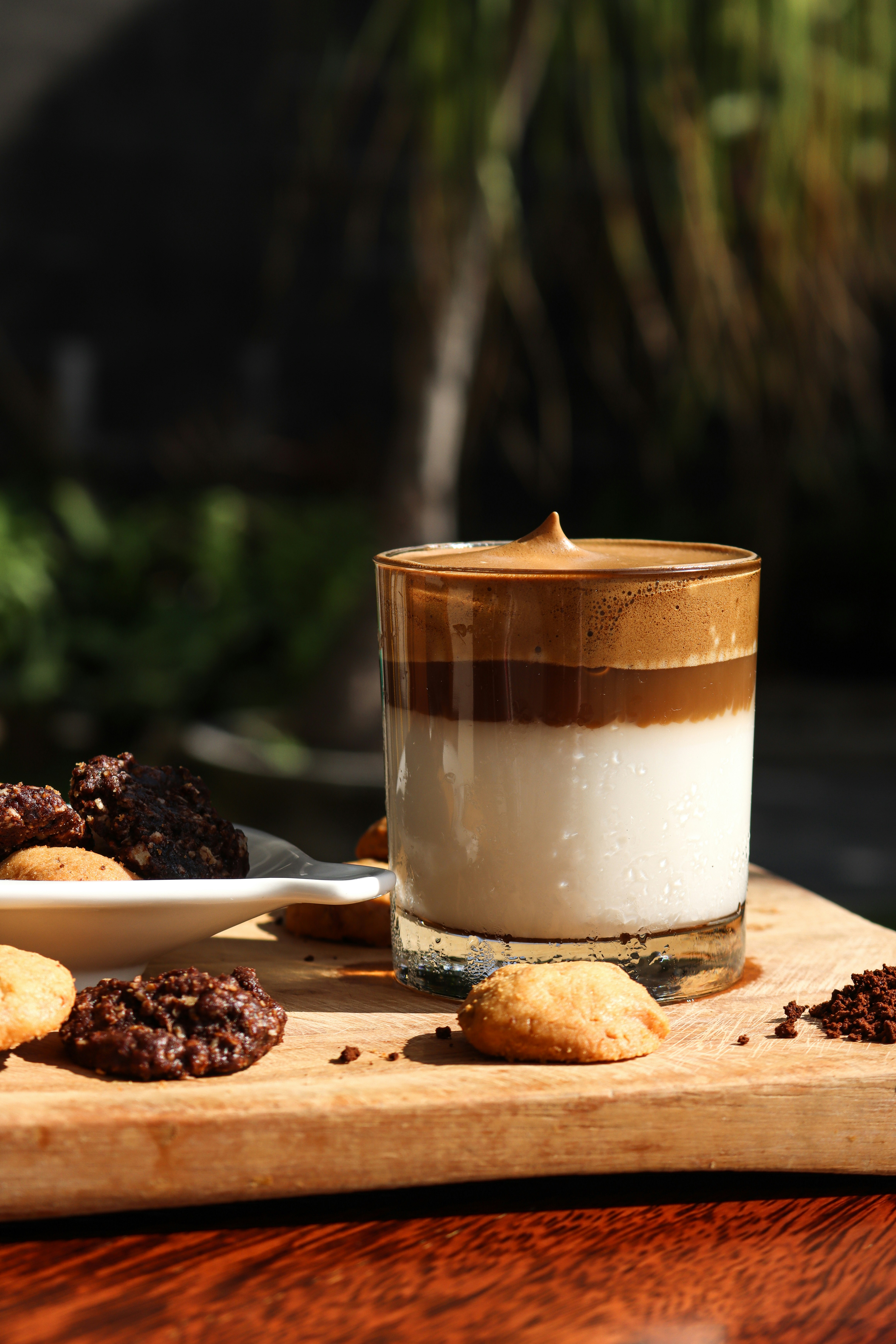 klares Trinkglas mit brauner Flüssigkeit auf braunem Holzschneidebrett