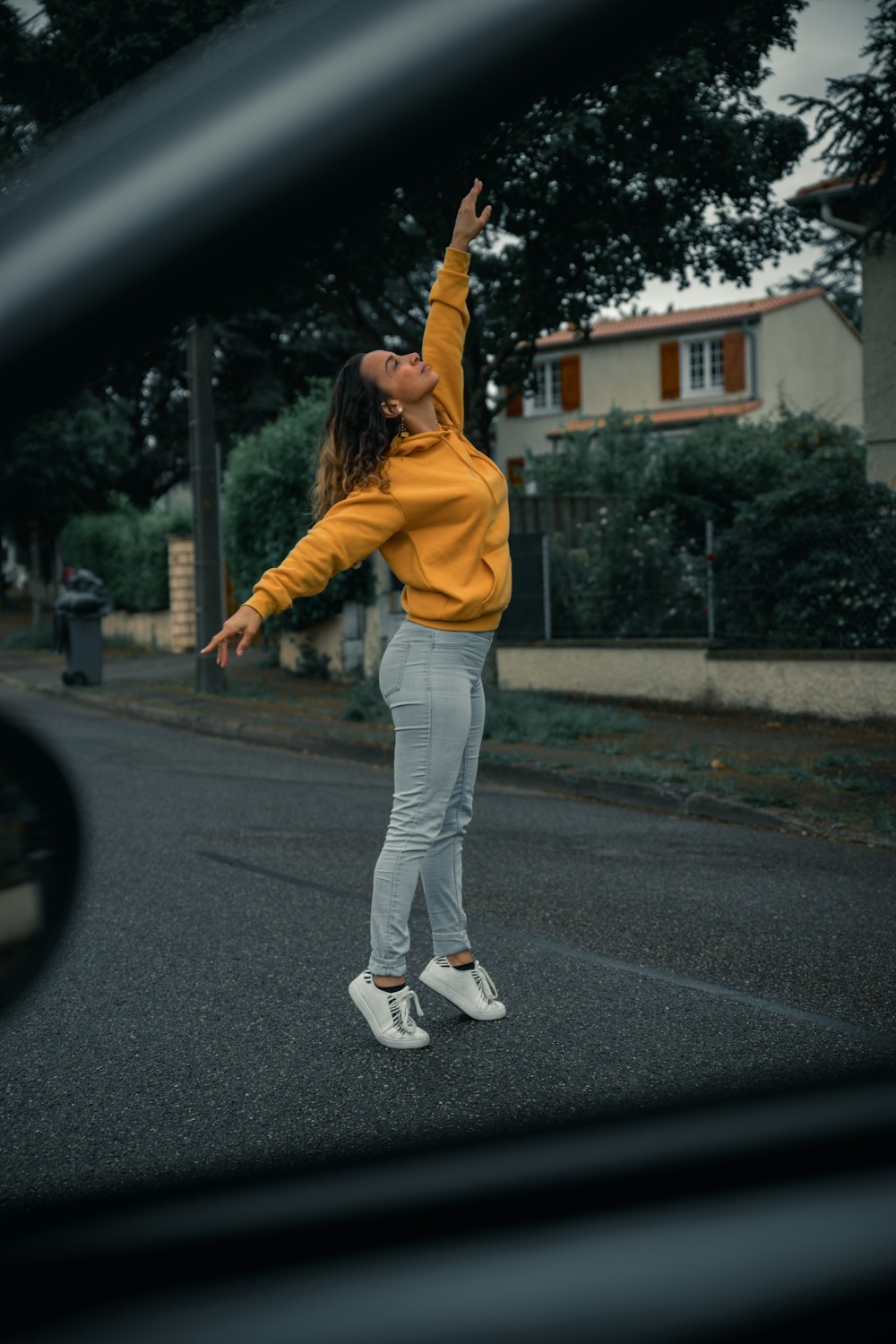 donna in giacca gialla e pantaloni bianchi che cammina per strada durante il giorno