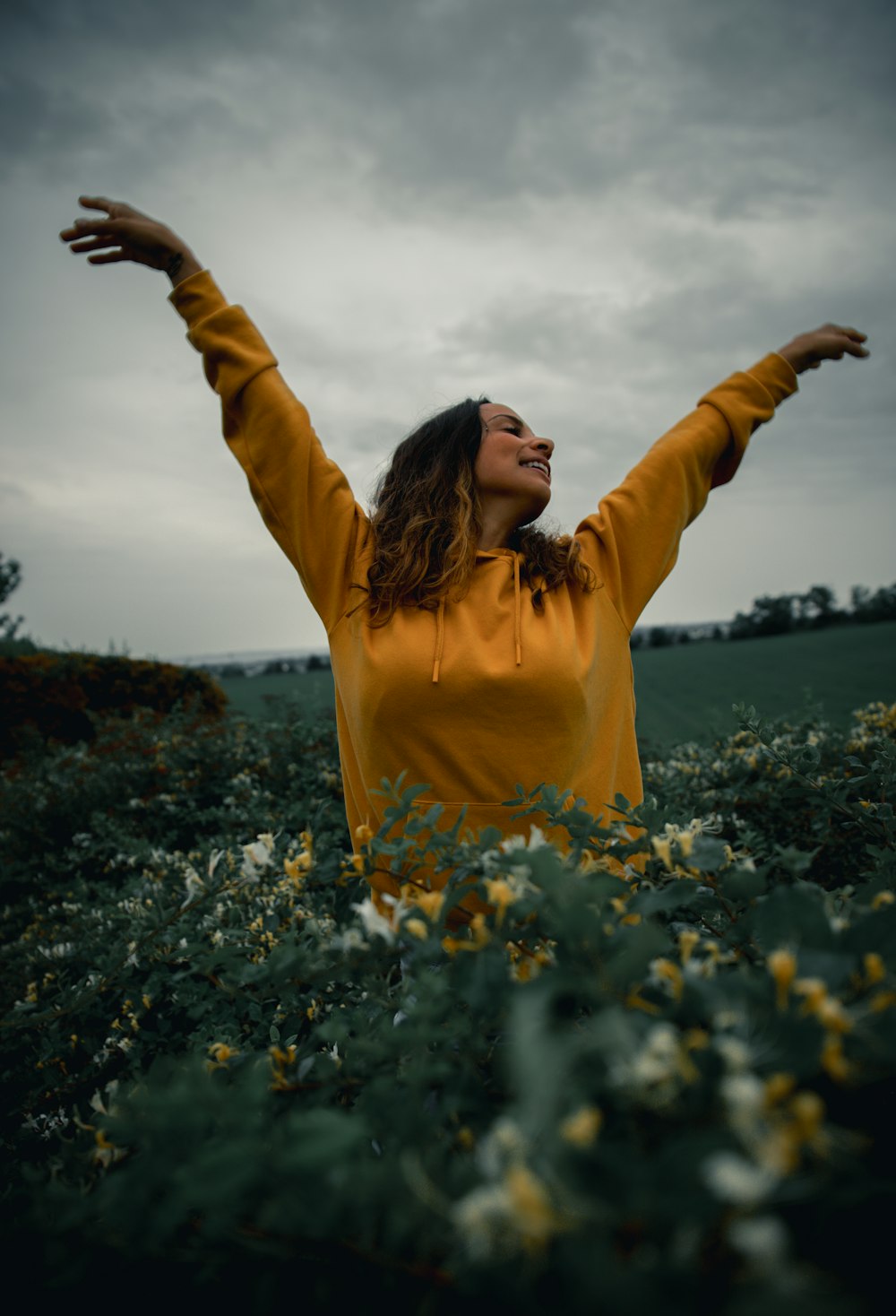 woman in yellow long sleeve shirt standing on flower field during daytime