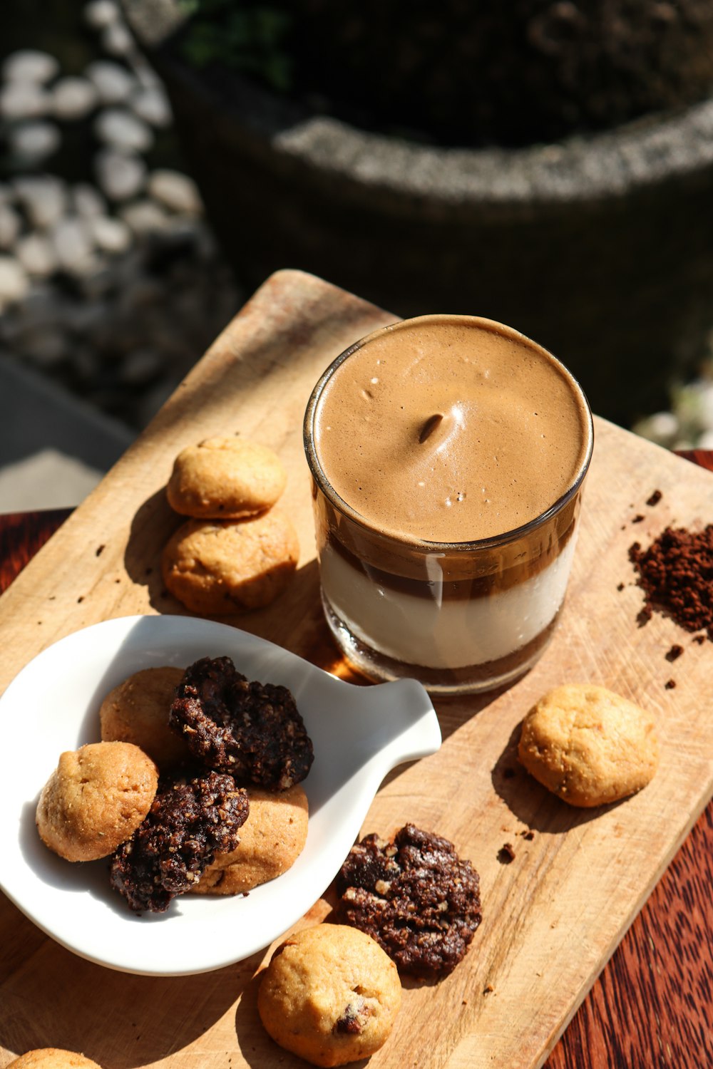 brown and white coffee in clear glass mug on brown wooden chopping board