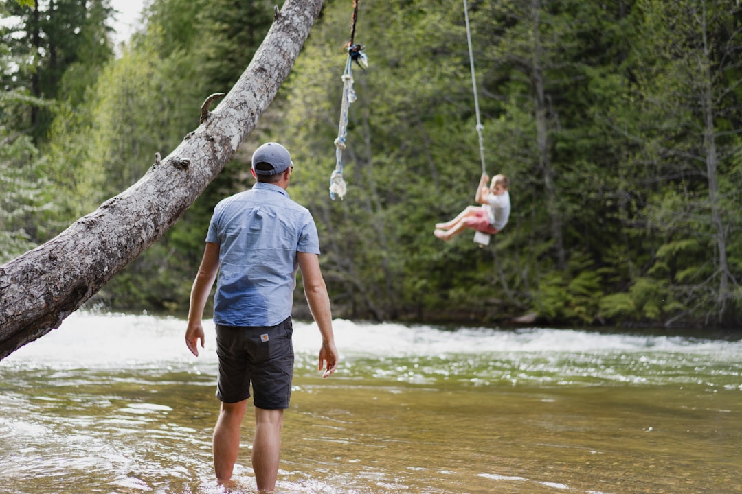 man in grey t-shirt and blue shorts standing on tree branch during daytime