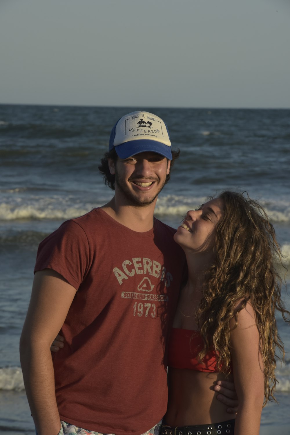 hombre y mujer sonriendo cerca del mar durante el día