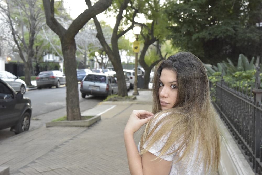 woman in white lace dress standing on sidewalk during daytime