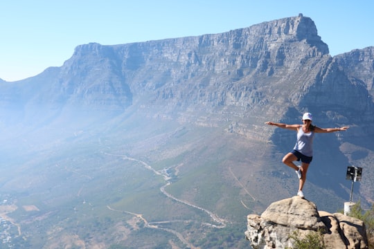 man in black t-shirt and brown shorts sitting on rock mountain during daytime in Table Mountain National Park South Africa