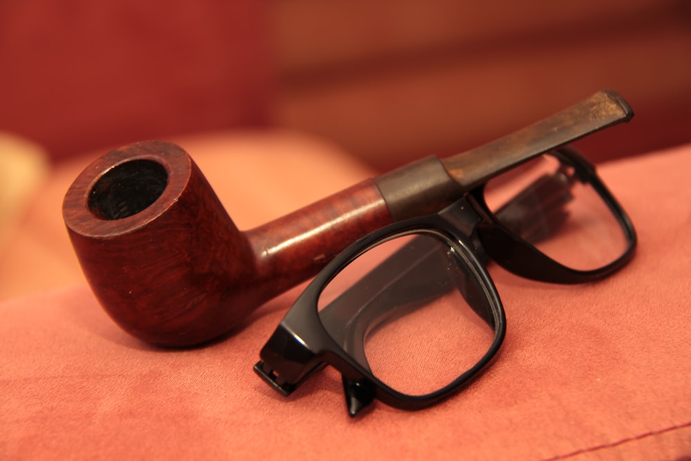 a pipe sitting on top of a couch next to a pair of glasses