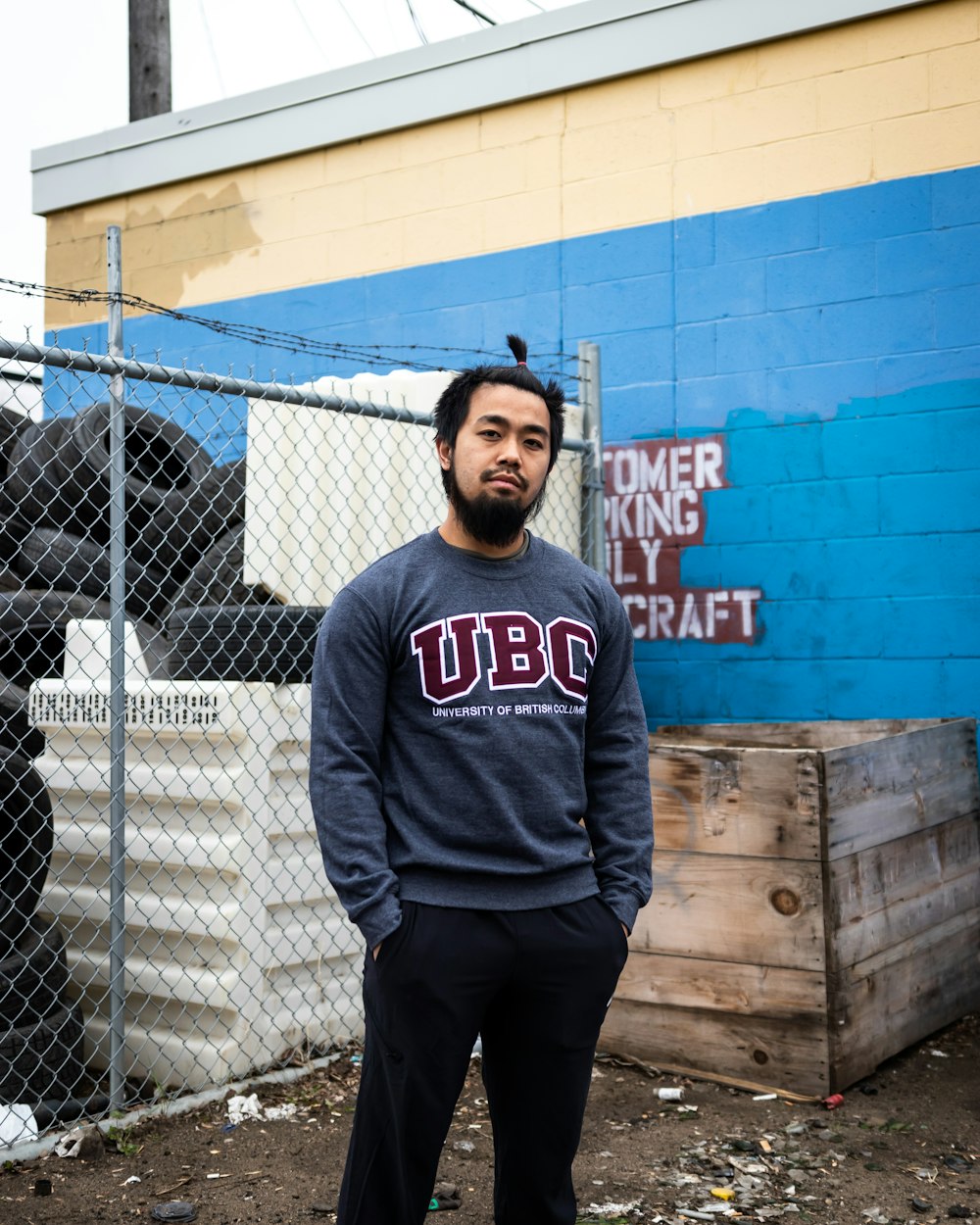 man in blue and white pullover hoodie standing beside chain link fence