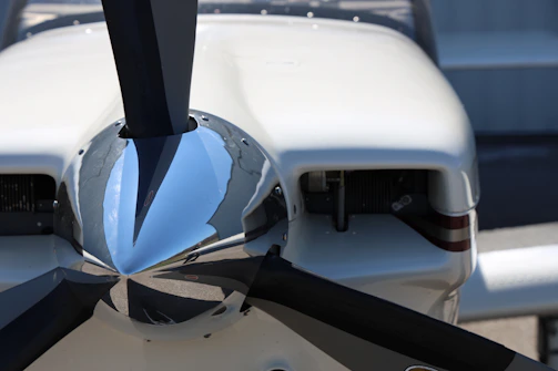 Close-up of a polished silver vintage airplane propeller gleaming against a dark blue background.