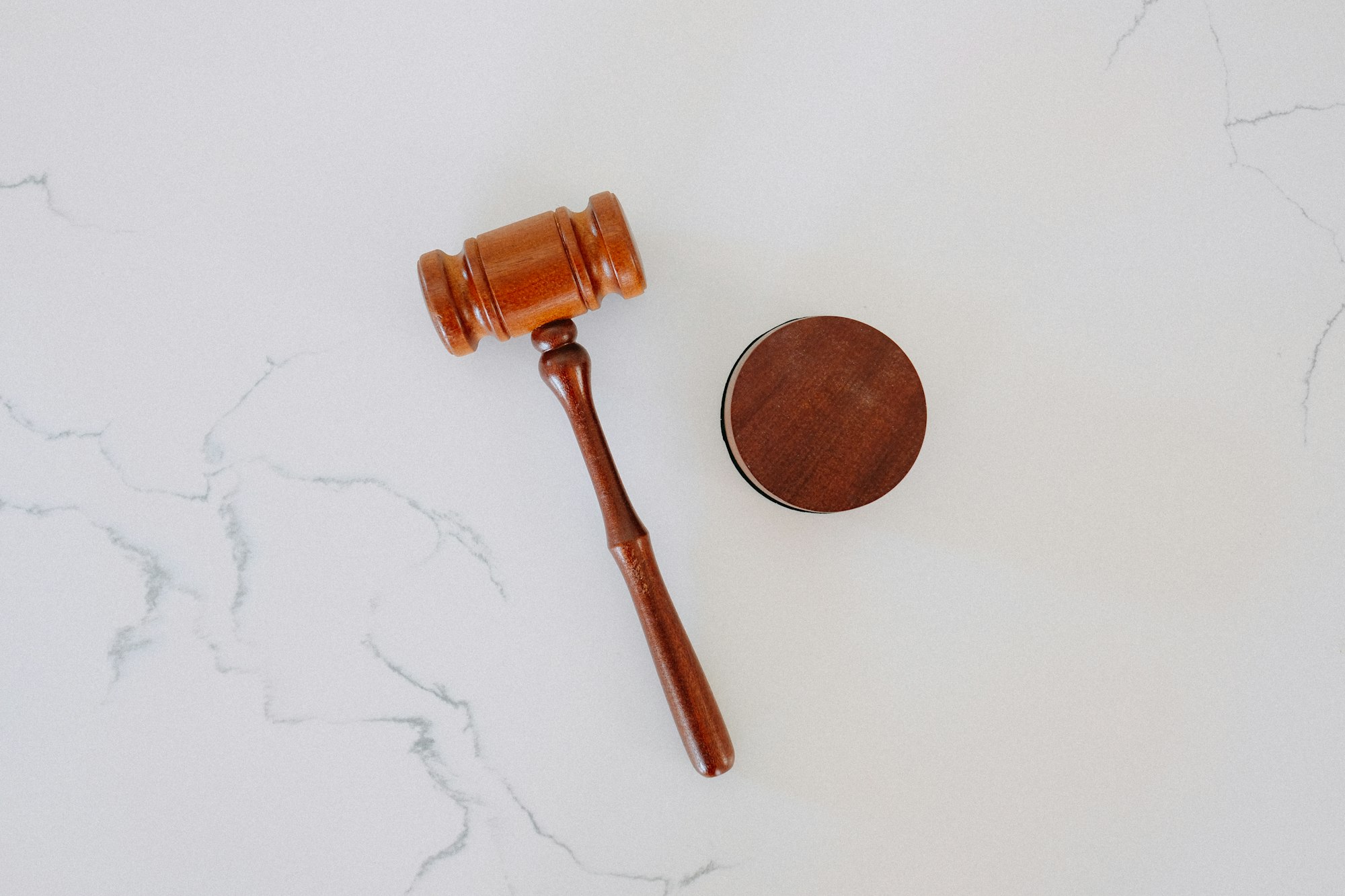 A legal wooden gavel on a white marble backdrop.