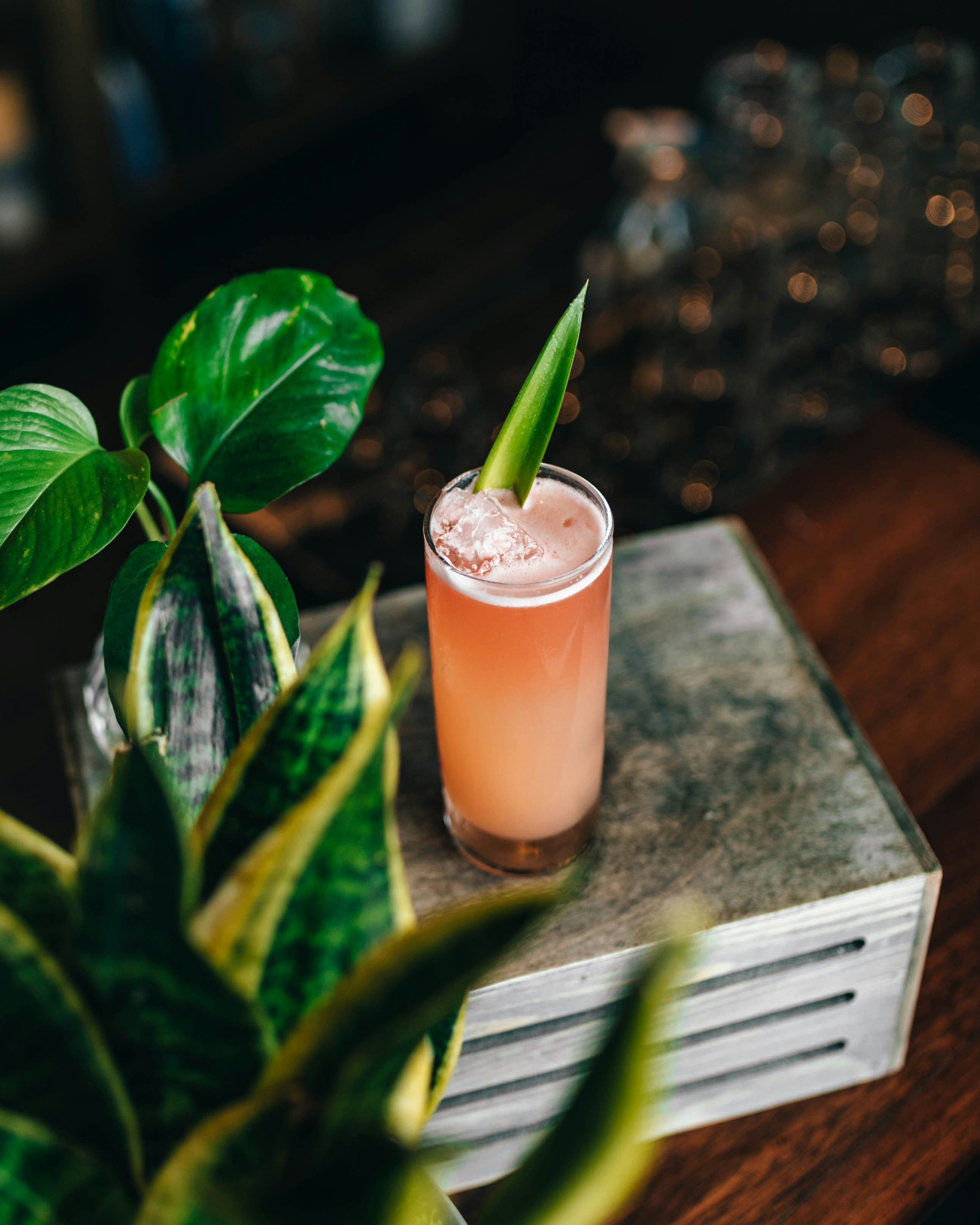 茶色の木製のテーブルにピンクの液体が入った透明なコップ