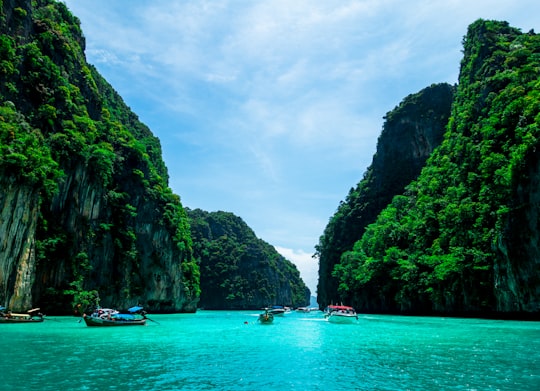 boats on sea near mountain during daytime in Phuket Thailand