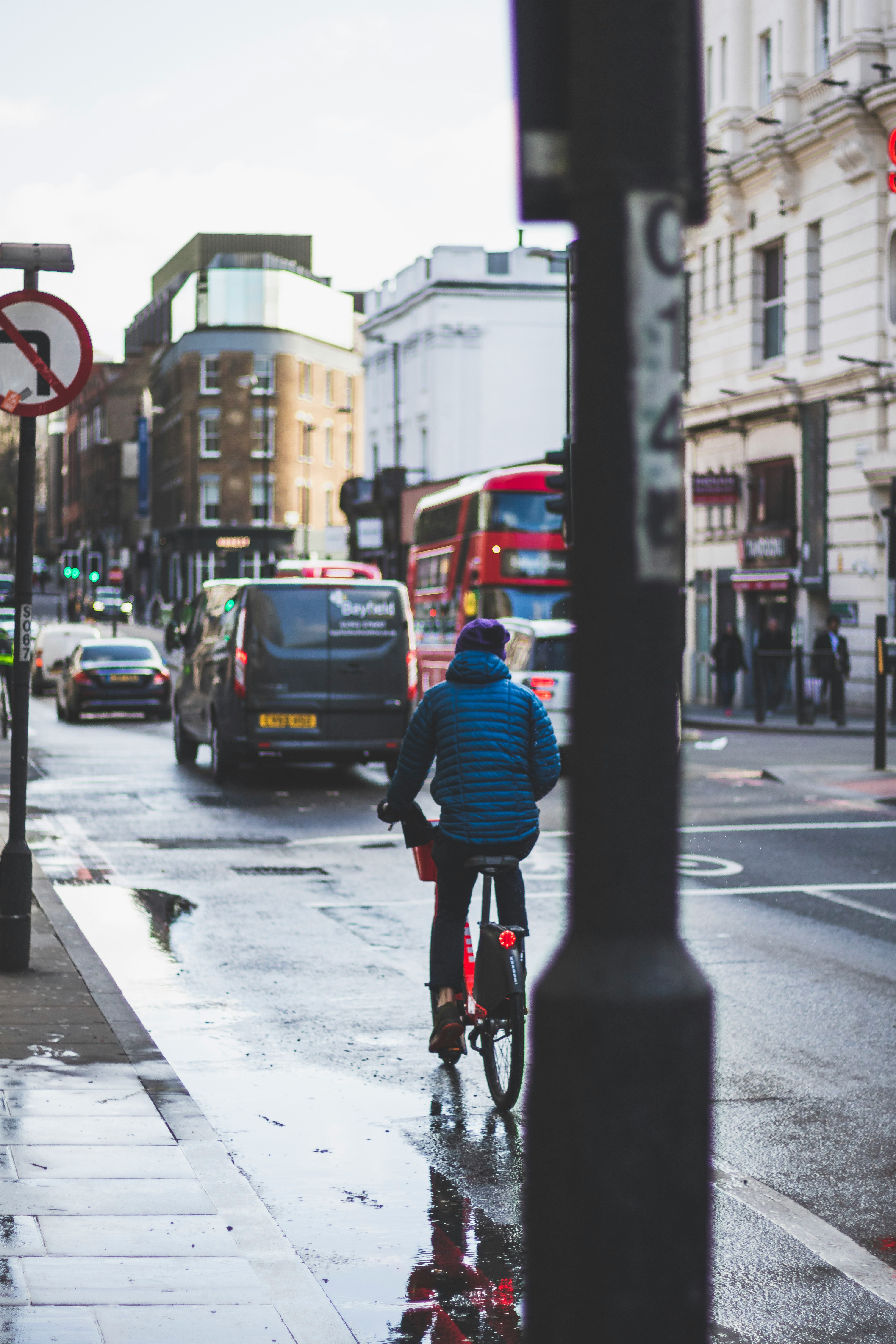 man in blue jacket riding bicycle on road during daytime