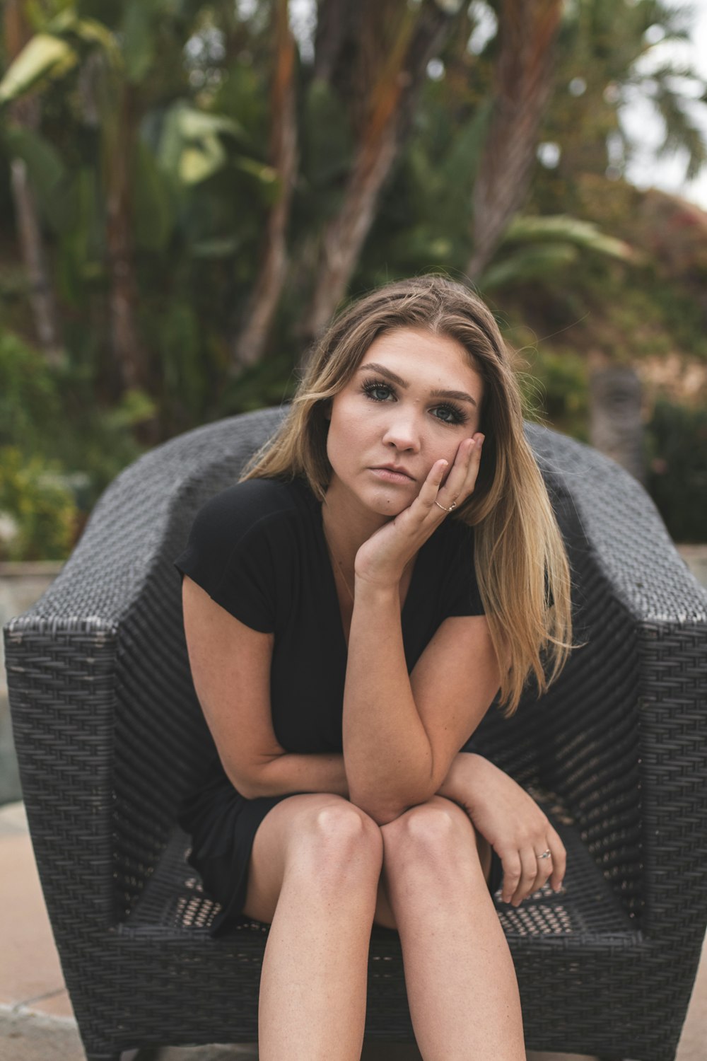 woman in black shirt sitting on gray wicker armchair