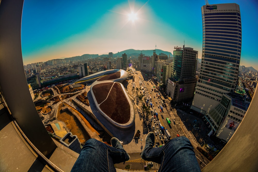 person in blue denim jeans and brown shoes sitting on top of building during daytime