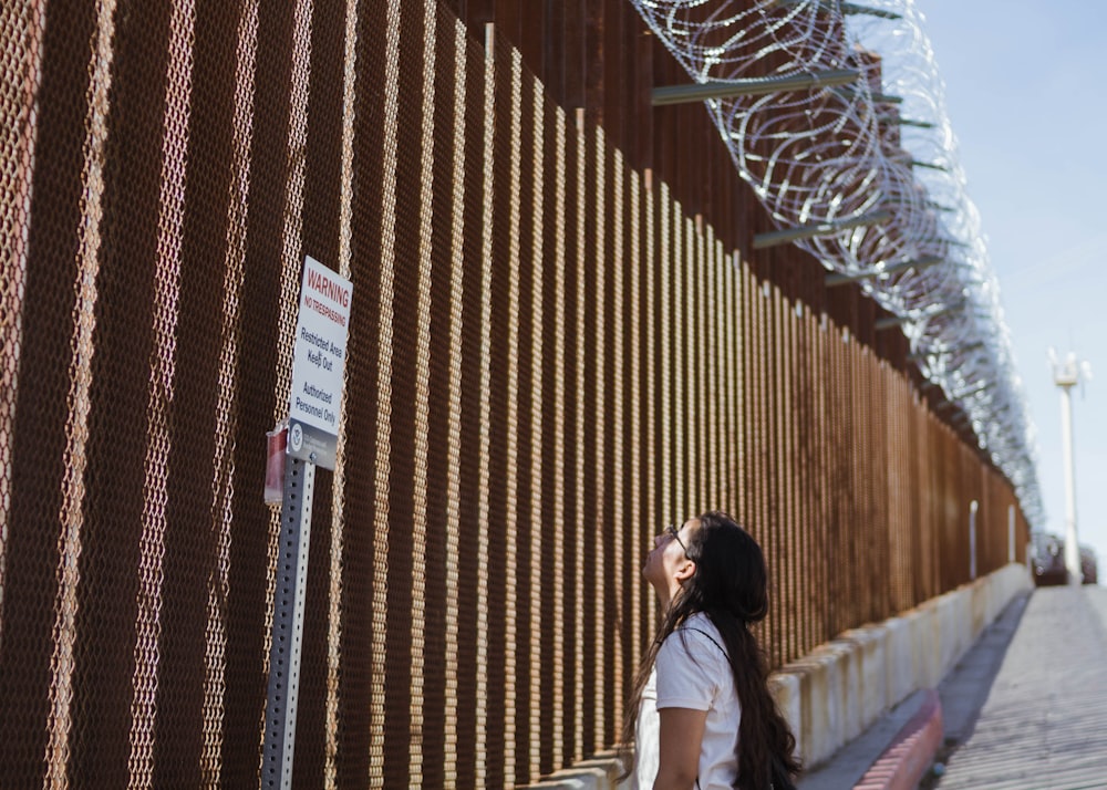 woman in white shirt standing on brown wooden bridge during daytime