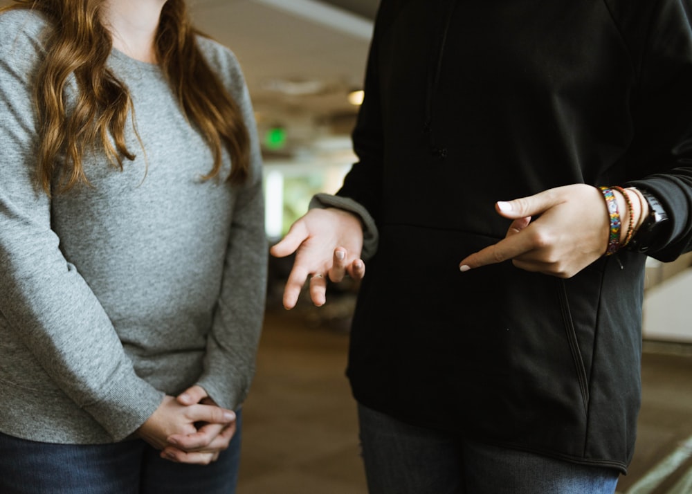 woman in gray sweater and blue denim jeans holding hands with woman in gray sweater