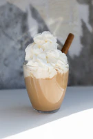 A seasonal specialty coffee topped with whipped cream and a sprinkle of cinnamon, glowing in natural light.
