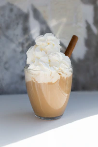 A creamy Asian dolce coffee topped with a dusting of cocoa powder and a cinnamon stick.