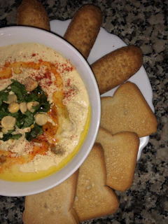 Golden, crispy hummus topped with olive oil and a sprinkle of paprika in a rustic bowl.