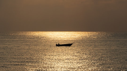 silhouette of person riding on boat on sea during sunset in Hengam Island Iran
