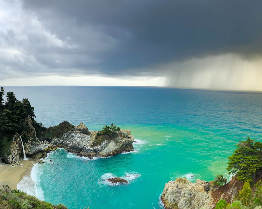 green and brown rock formation on blue sea under white clouds during daytime