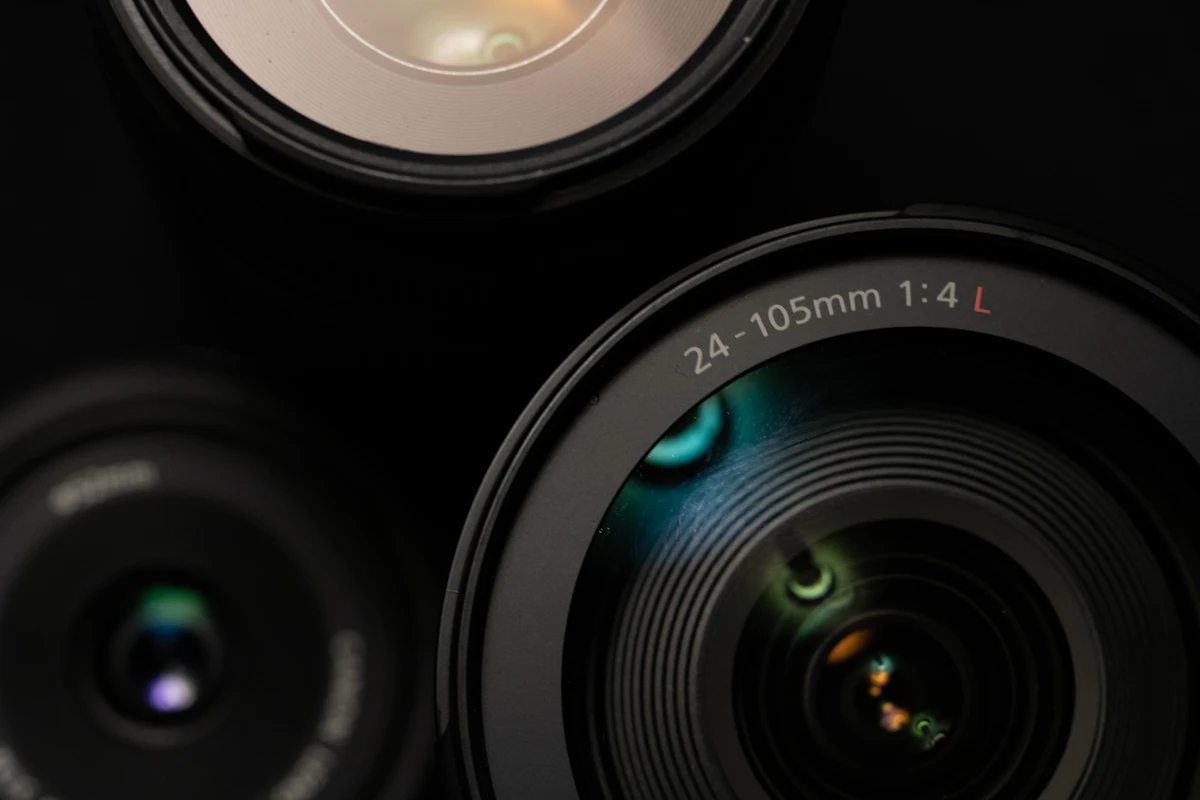 Close-up of a Canon 24-105mm 1:4 L lens barrel showing the focal length and aperture markings alongside another Canon lens