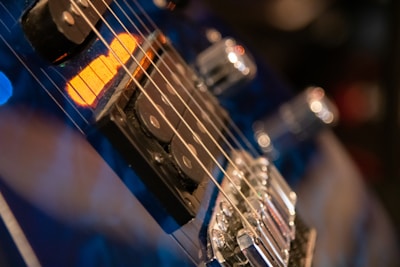 Close-up view of an electric guitar focusing on the strings, pickups, and controls with a warm, moody lighting.