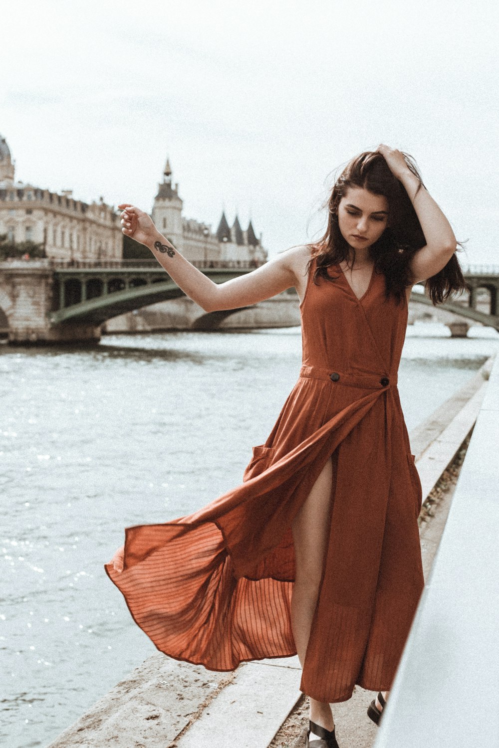 Frau in rotem ärmellosem Kleid steht tagsüber auf der Brücke