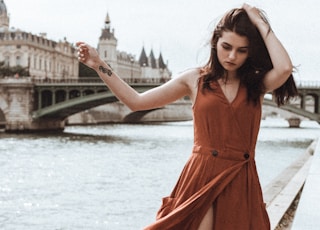 woman in red sleeveless dress standing on bridge during daytime