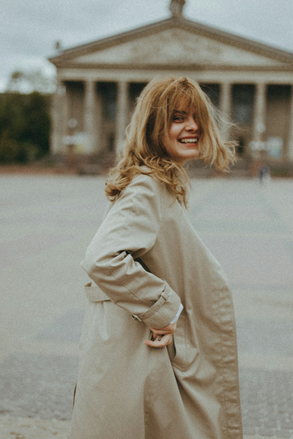 woman in beige coat standing on road during daytime