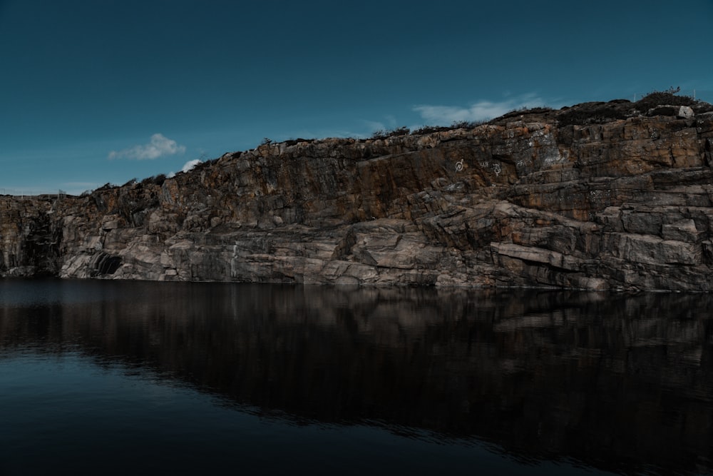 brown rocky mountain beside body of water during daytime