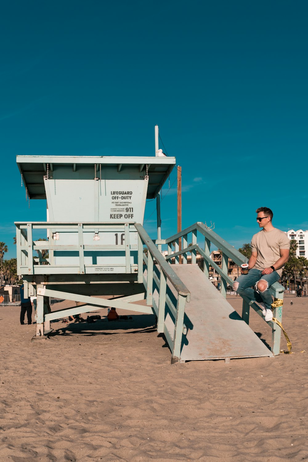 man in gray t-shirt and black pants sitting on white wooden stairs during daytime