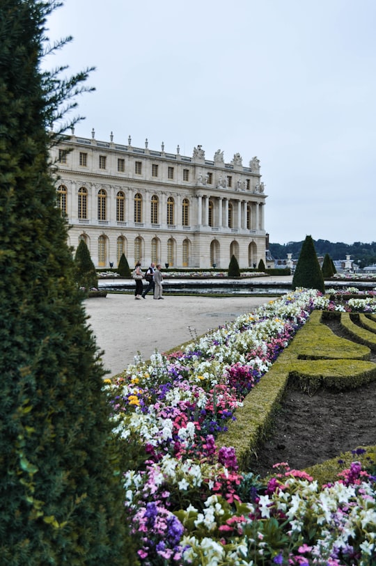 people walking near brown concrete building during daytime in Palace of Versailles France