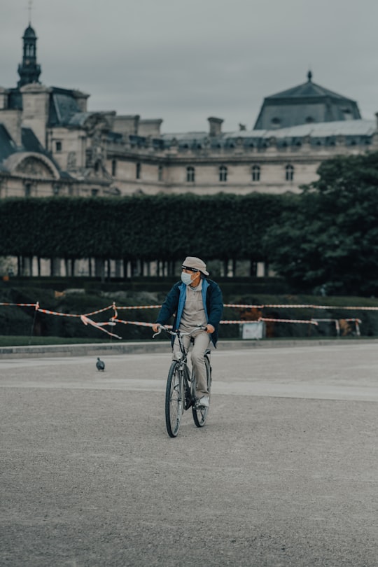 man in blue denim jacket riding bicycle on road during daytime in Tuileries Garden France