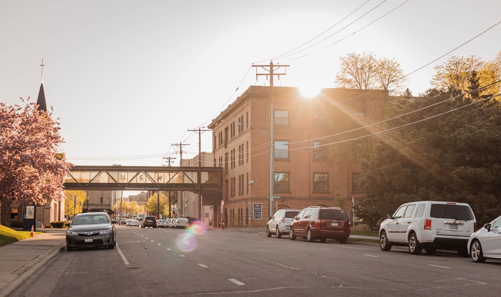 cars parked on side of the road near brown concrete building during daytime