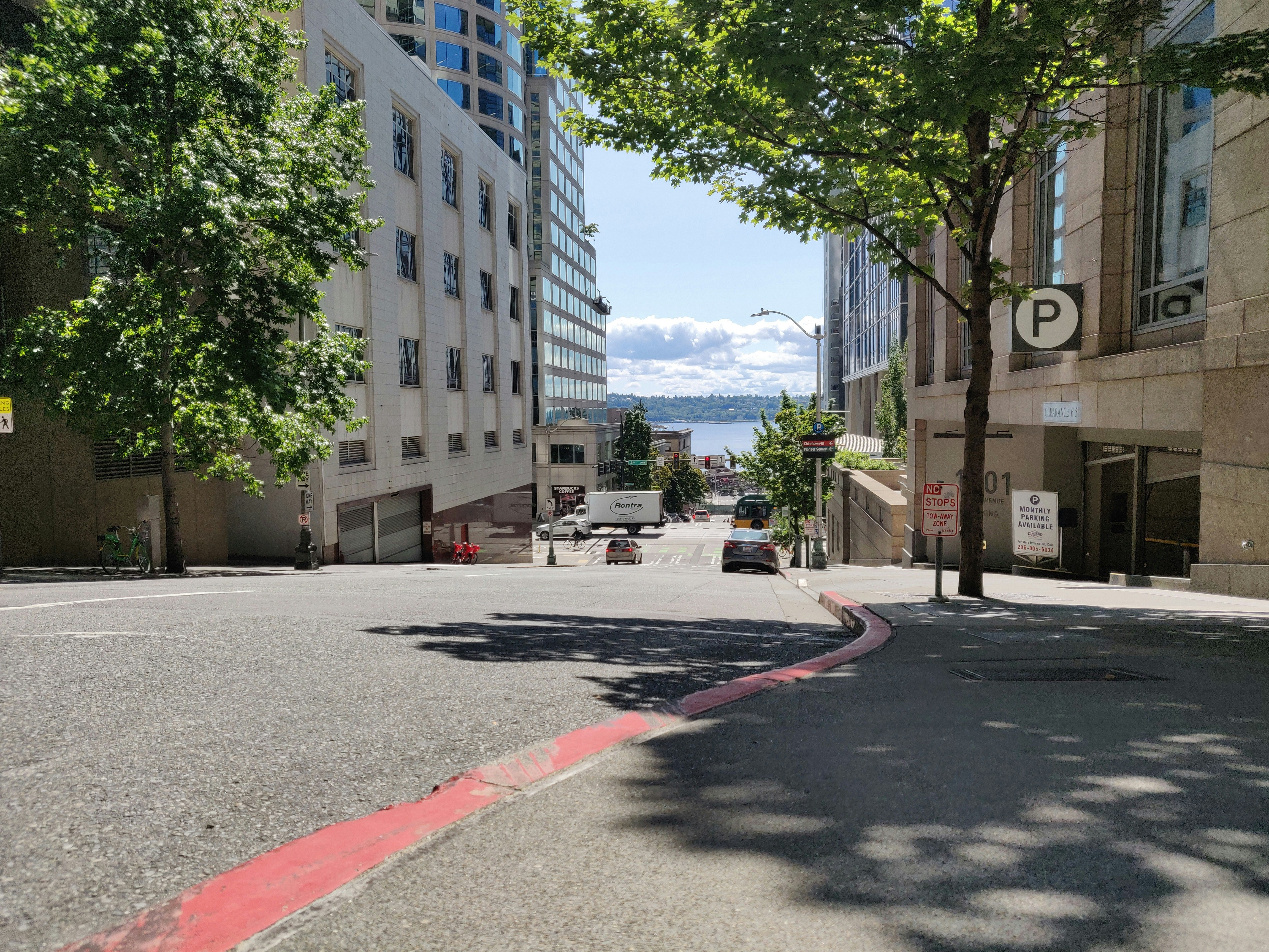 cars parked on side of the road near high rise buildings during daytime