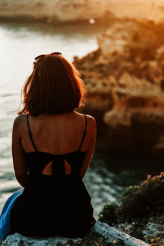 woman in black spaghetti strap top standing near body of water during daytime in Carvoeiro Portugal