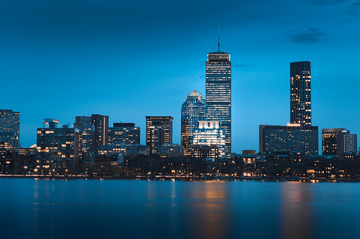 Boston skyline at dusk with city lights reflecting on the water