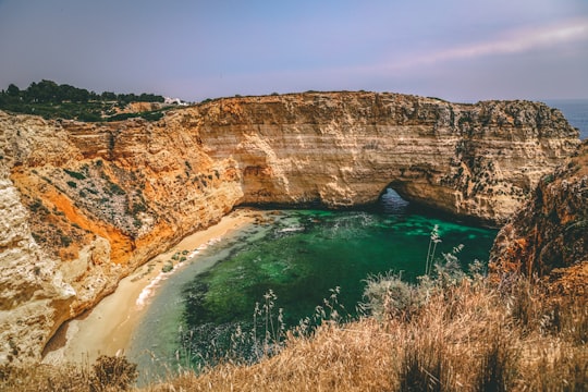 brown rock formation beside blue sea during daytime in Carvoeiro Portugal