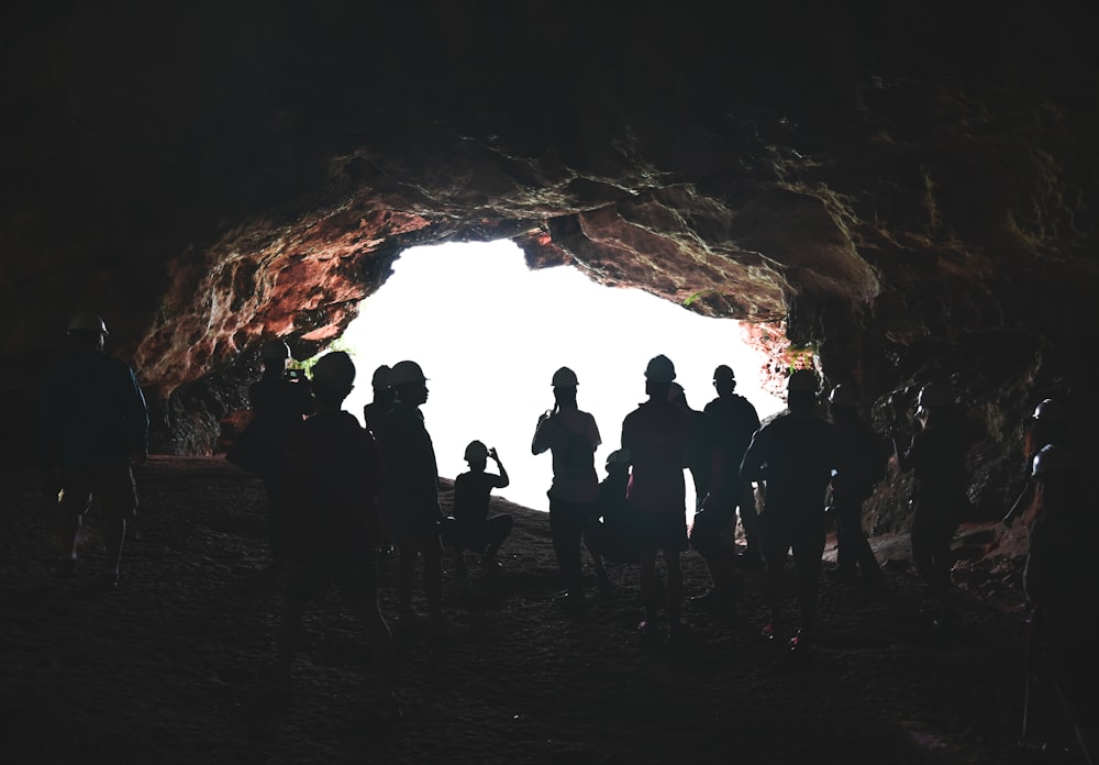 silhouette of people standing on cave