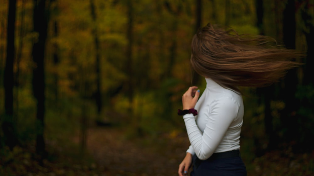 woman in white long sleeve shirt and blue denim jeans holding black smartphone